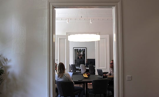 Wide view through a doorway of a team meeting in a modern office